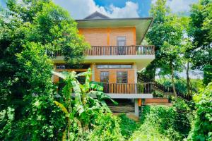 a house with a balcony in the middle of trees at Nui Tuong Village Stay in Tân Phú