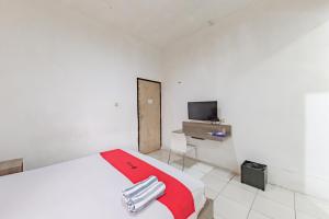 Cette chambre blanche comprend un lit et une télévision. dans l'établissement RedDoorz near Taman Kota Lapang Merdeka Sukabumi, à Sukabumi