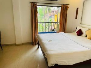 a bedroom with a large bed and a window at The merit resort in Arpora