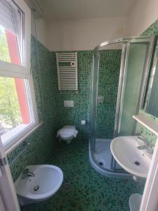 baño verde con 2 lavabos y ducha en HOTEL VILLA SANTANNA, en Rímini