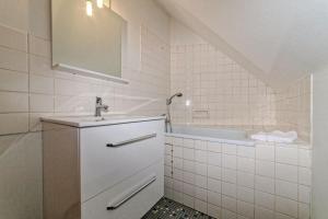 La salle de bains blanche est pourvue d'un lavabo et d'une baignoire. dans l'établissement Maison 15 couchages idéale pour séjour en groupe, à Clermont-Ferrand