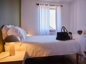 Un dormitorio con una cama blanca con una bolsa negra. en Appartamento Filippo en Baveno