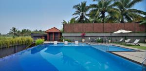 een groot blauw zwembad naast een huis bij Citadines Arpora Nagoa Goa in Arpora