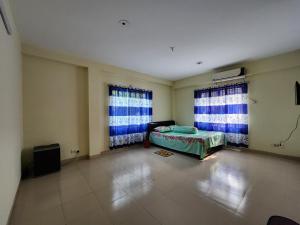 Cette chambre comprend un lit et deux fenêtres. dans l'établissement Aaira guest house, à Dhaka