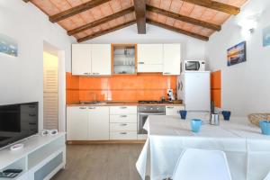 una cucina con armadietti bianchi e frigorifero bianco di Casa Arancio a SantʼIlario in Campo
