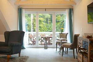 - un salon avec une porte coulissante en verre, une table et des chaises dans l'établissement Strandhäuser Blankenfohrt, à Ückeritz