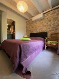 ein Schlafzimmer mit einem lila Bett und einer Steinmauer in der Unterkunft La Grange de Camille in Loupiac