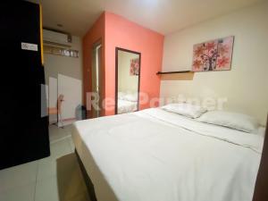 1 dormitorio con cama blanca y pared de color naranja en Audah Guesthouse Syariah Kuningan RedPartner, en Yakarta