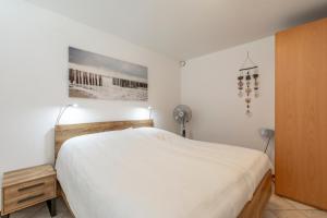 een slaapkamer met een wit bed en een ventilator bij Wijde Blick appartement 211 - Callantsoog in Callantsoog