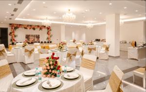 une salle de banquet avec des tables blanches et des chaises blanches dans l'établissement Triptam Vrindavan, à Vrindavan