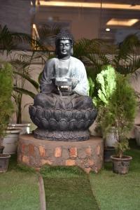 a statue of a buddha sitting in a fountain at HOTEL YASH PALACE in New Delhi