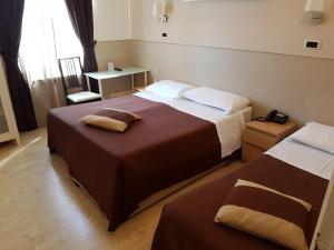 a hotel room with two beds and a table at Hotel Indipendenza in Rome