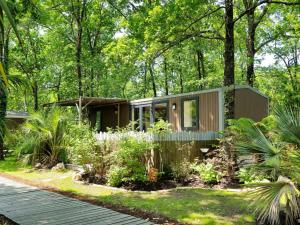 ein kleines Haus im Wald mit Bäumen in der Unterkunft Camping Aux Couleurs du ferret in Lège-Cap-Ferret