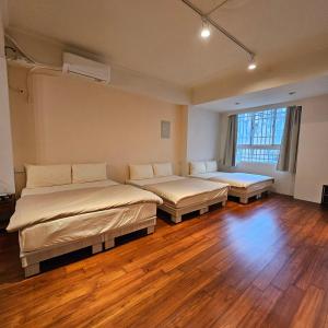 2 camas en una habitación con suelo de madera en Maybe Homestay, en Longjing