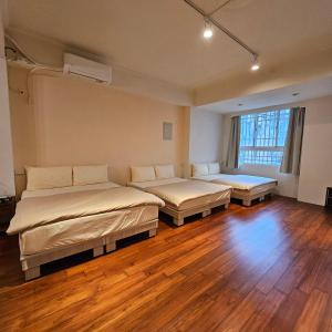 two beds in a room with wooden floors at Maybe Homestay in Longjing