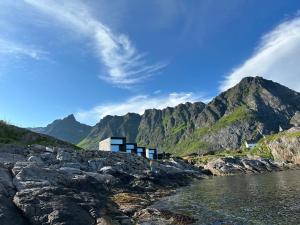 a building on a rocky hill next to a body of water at High end sea cabins at Å in Lofoten in Moskenes