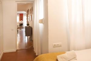 a white bedroom with a bed and a hallway at Apartamento Alfaqueque in Seville