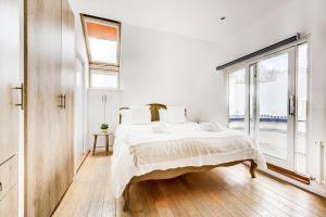 a white bedroom with a large bed and a window at Duplex Apartment Shoreditch - the Living Elite Collection in London