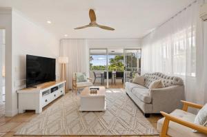 a living room with a couch and a flat screen tv at Yaringa Noosa Heads - Ocean View, Walk to Beach in Noosa Heads