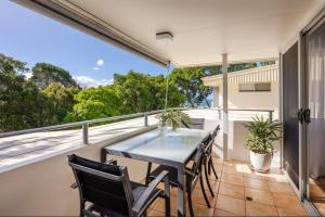 a patio with a table and chairs on a balcony at Yaringa Noosa Heads - Ocean View, Walk to Beach in Noosa Heads