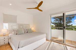 a white bedroom with a bed and a ceiling fan at Yaringa Noosa Heads - Ocean View, Walk to Beach in Noosa Heads