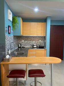 cocina con encimera de madera y 2 taburetes en Aqua Inn - Studio Apartment, en Greater Noida