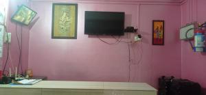 a living room with a pink wall with a television on it at Hotel Kaziranga Holidays in Kāziranga