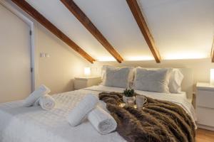 Un dormitorio con una gran cama blanca con toallas. en Únika Homes Porvenir, en Sevilla