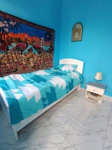 um quarto azul com uma cama com uma tapeçaria na parede em Dar Hkaïem em Sousse