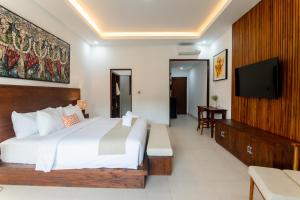 a bedroom with a large bed and a flat screen tv at Griya Shanti Suites in Sanur