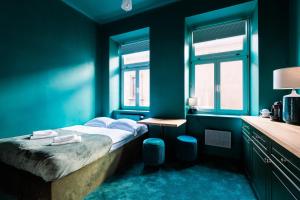 een blauwe slaapkamer met een bed en 2 ramen bij Green Gertrudy in Krakau