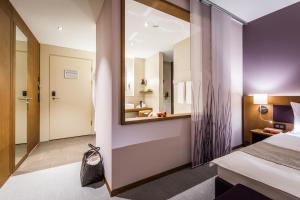 ein Hotelzimmer mit einem Bett und einem Spiegel in der Unterkunft Deltapark Vitalresort**** in Thun
