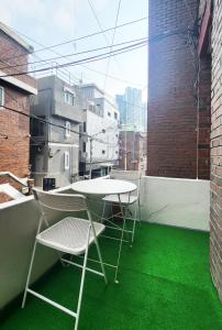 Duas cadeiras e uma mesa numa varanda com piso verde em New Corestay # Edae Stn 2min 2R 2F # near Hongdae em Seul
