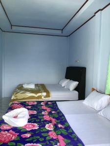 duas camas num pequeno quarto com uma colcha em Matraville guesthouse em Tuktuk Siadong