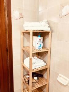 - une étagère en bois dans la salle de bains pourvue de serviettes dans l'établissement Casa Praiola, à Terrasini