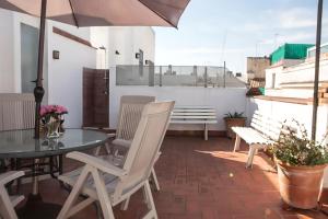 un patio con mesa, sillas y sombrilla en Malhara, en Sevilla