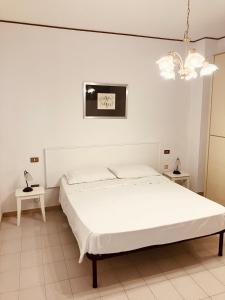 Habitación blanca con cama y lámpara de araña. en Casa Praiola, en Terrasini