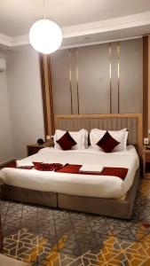 ein Schlafzimmer mit einem großen Bett mit roten und weißen Kissen in der Unterkunft GOLDEN NEW UMU ALQURAA Hotel in Dschidda