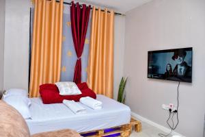 uma sala de estar com uma cama e uma televisão em JoJo Jovial Homes em Kiambu