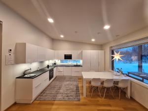 uma cozinha com armários brancos e uma mesa e cadeiras em Villa Arctic Light em Rovaniemi