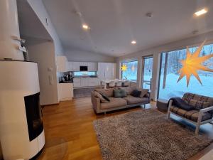 a living room with two couches and a kitchen at Villa Arctic Light in Rovaniemi