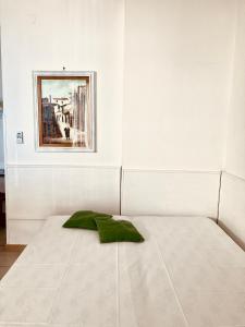 un letto bianco con un cuscino verde sopra di Casa Praiola a Terrasini