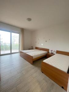 1 Schlafzimmer mit 2 Betten und einem großen Fenster in der Unterkunft RESIDENCE PANFILO - WALTERIGATO Apartments SOLO PER FAMIGLIE in Lido di Jesolo