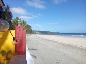 a beach with a yellow and red building and the ocean at Koa's Beach House in Tangalan