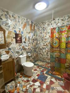 a bathroom with a toilet and a mosaic wall at Koa's Beach House in Tangalan