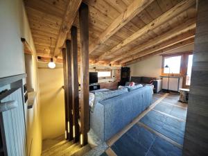 a living room with a blue couch and wooden ceilings at Hostdomus - Chalet Sun in Sestriere