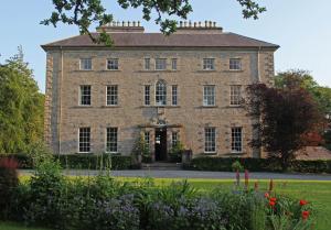 una vieja casa de ladrillo con flores en primer plano en Coopershill House, en Riverstown