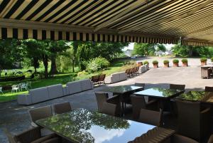 un patio al aire libre con mesas, sillas y un gran patio en Résidence de la Roseraie, en Florenville