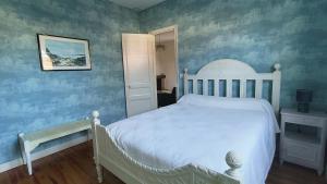 a bedroom with a white bed and blue walls at Maison "Sarah Bernhardt" in Andernos-les-Bains