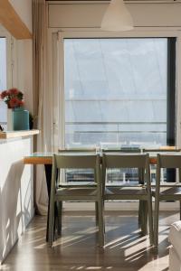 バダロナにあるGran Apartmento Playa Badalonaのダイニングルーム(テーブル、椅子付)、大きな窓が備わります。